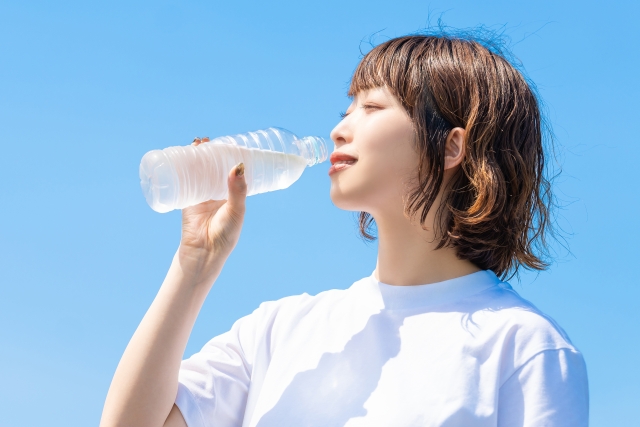 唾液の分泌を増やすため水分補給をしている女性